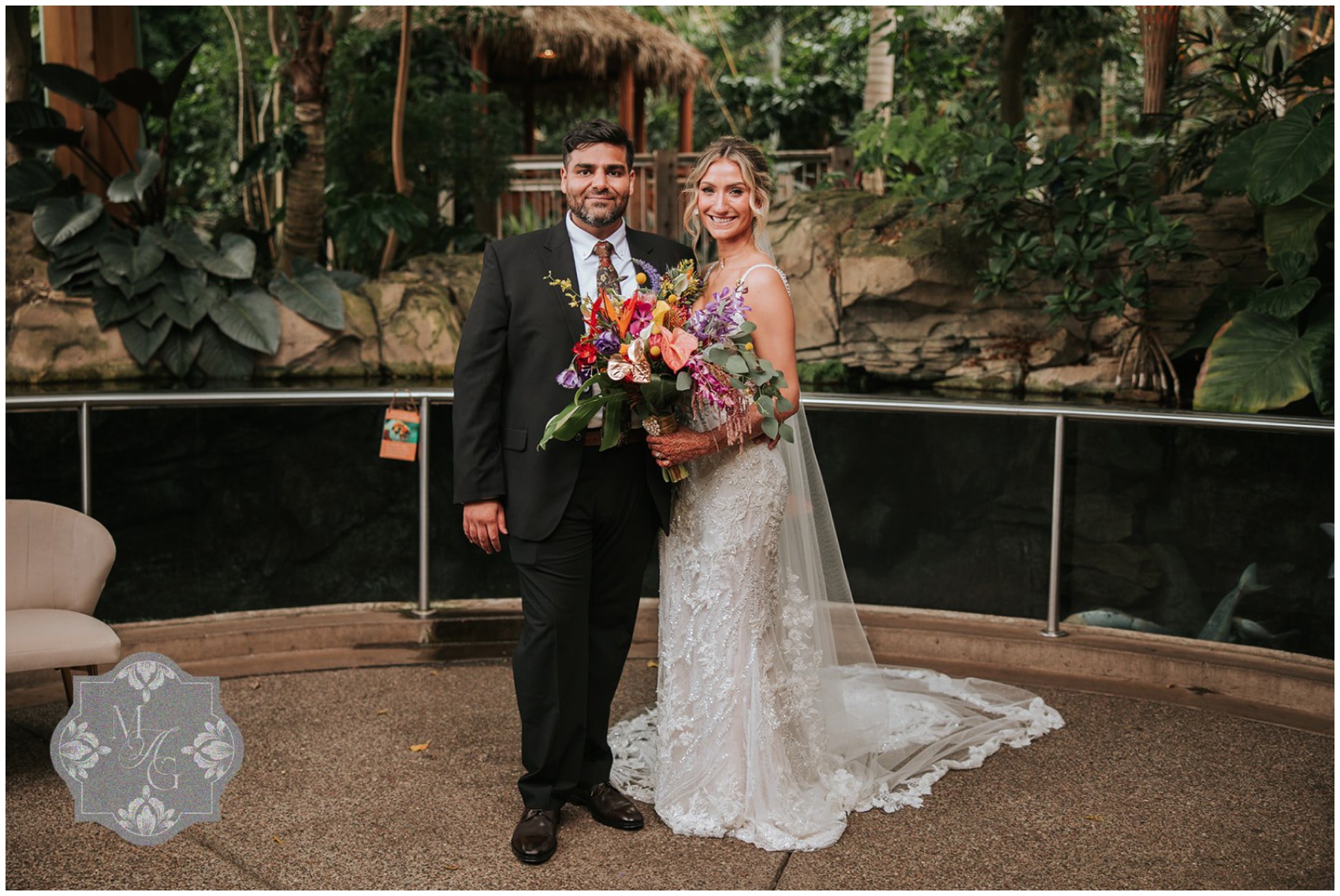 Newlyweds stand in the gardens holding a colorful large bouquet at their Phipps Conservatory wedding